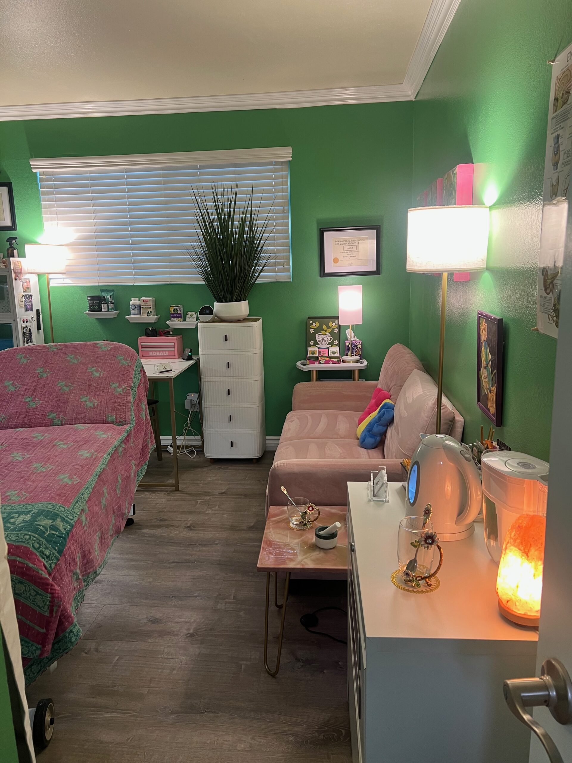 Cozy bedroom with green walls, a bed, and a sitting area with soft lighting.